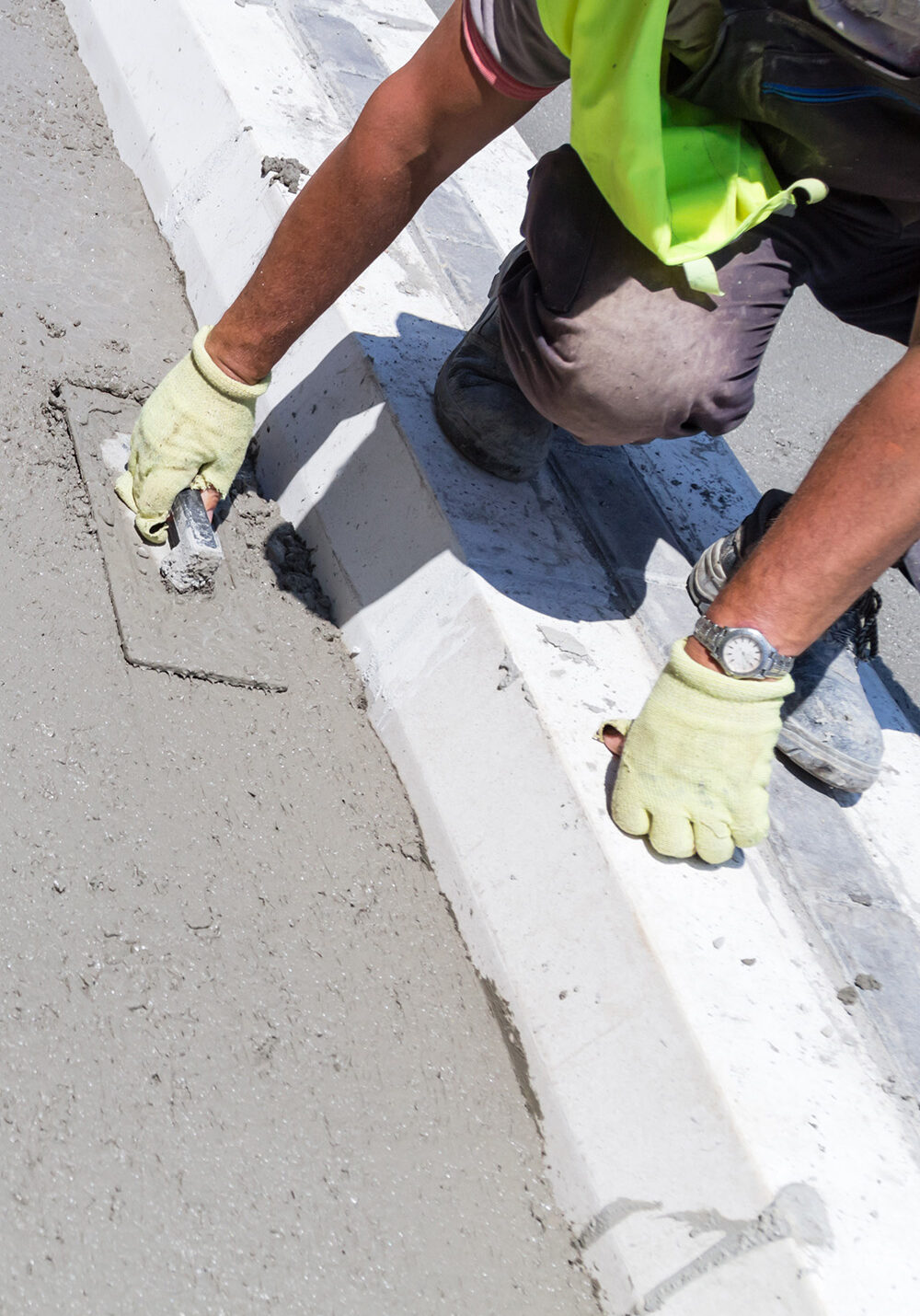 D&G Cement Company worker finishing commercial curbs and gutters next to a newly paved parking lot in Northville