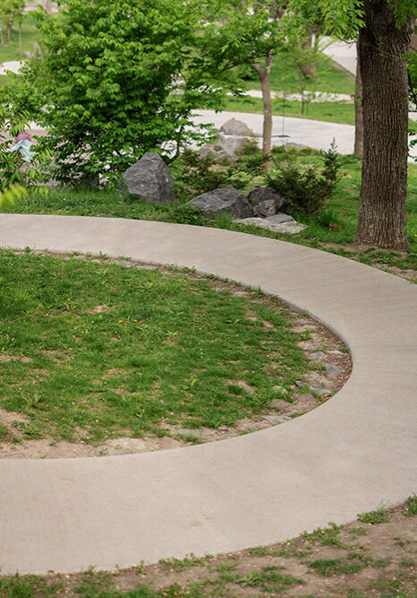 A smooth, perfectly curved concrete walkway installed by D&G Cement Company in Westland MI through a park landscape
